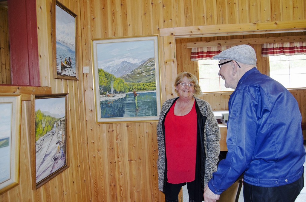 Leif Johannessen, her sammen med Anne-Gerd Jonassen, studerer bildene til den lokale kunstneren Helge Mikalsen nøye. Spesielt maleriet som viser et gjeng arbeidskarer som driver veibygging, får Johannessens minner til å flomme. KUVA HEIDI NILIMA MONSEN